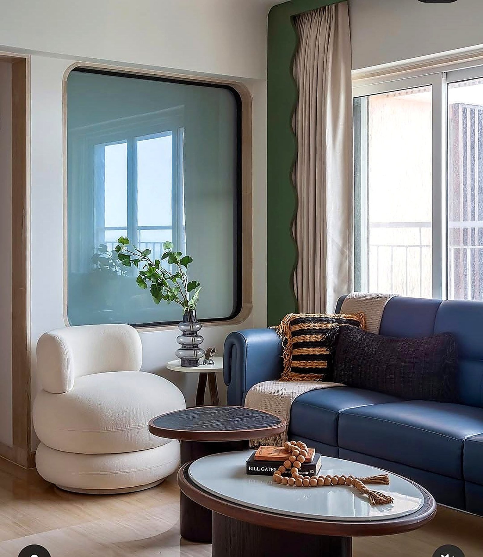 Living room with a sage curtain and curved white armchair